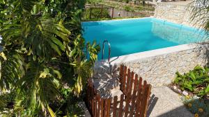 a swimming pool with a stone wall and a wooden fence at Casa Verdelho in Palmela