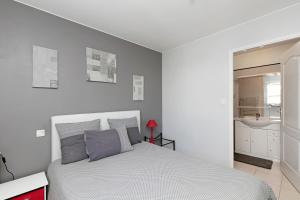 a white bedroom with a bed and a bathroom at Chambres d'Hôtes - Les Boubous in Saint-Nazaire