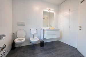 a white bathroom with a toilet and a sink at Avia Living in Brunico +10 photos