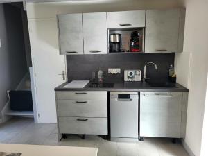 a small kitchen with white cabinets and a sink at Jolie Maison Cyprange in Pirou +19 photos