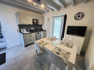 a kitchen with a table with chairs and a clock on the wall at Jolie Maison Cyprange in Pirou