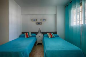 two twin beds in a room with blue sheets at Brasil Mar in Playa de Gandia