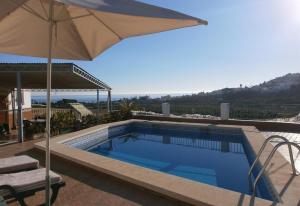a swimming pool with an umbrella and a table and a chair at El Puntal de Nieves in Nerja