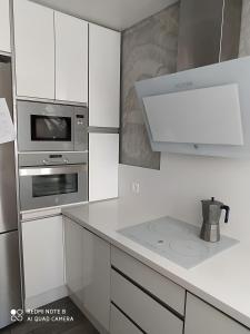 a kitchen with white cabinets and a stove top oven at Alojamiento Patricia in Igualeja