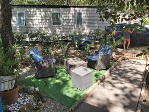 a woman standing in a backyard with chairs and tables at Mobilhome Topaze in Puget-sur-Argens