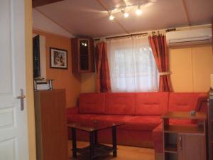 a living room with a red couch and a table at Mobilhome Topaze in Puget-sur-Argens