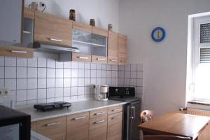 a kitchen with wooden cabinets and a clock on the wall at Ferienwohnung Rose in Schöneck +7 photos