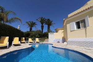a swimming pool with chairs and a house at Villa Carvoeiro Ceu in Lagoa