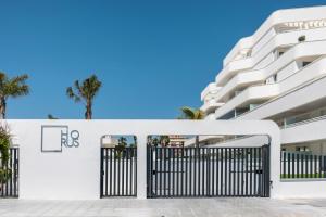 a white building with a gate and palm trees at Horus 051 in Torre del Mar