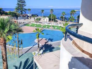 an overhead view of a swimming pool with palm trees and the ocean at Costamar Oceanview 1 Bed Apartment in Arona
