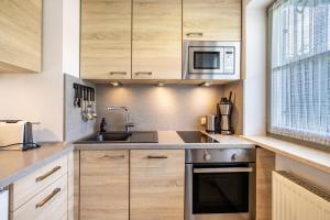 a kitchen with wooden cabinets and a sink and a microwave at Fewo Brünnstein - Nr 13 Pool, Sauna in Oberaudorf +10 photos