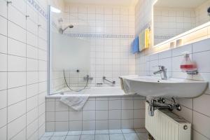 a white bathroom with a sink and a tub at Fewo Brünnstein - Nr 13 Pool, Sauna in Oberaudorf
