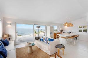 a white living room with a white couch and a kitchen at Casa da Praia Valmitão in Ribamar