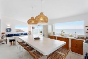 a kitchen with a large white table and some chairs at Casa da Praia Valmitão in Ribamar