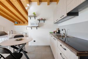 a kitchen with a table and a small kitchen with white cabinets at Il Nido Del Colibrì in Stazzona +29 photos