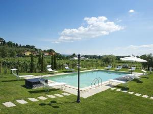 a large swimming pool with chairs and an umbrella at Villa con piscina in Capannori