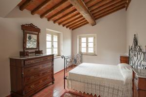 a bedroom with a bed and a dresser and windows at Villa con piscina in Capannori +30 photos