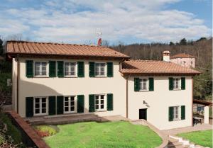 a white house with green shutters and a yard at Villa con piscina in Capannori