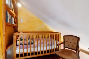 a crib and a chair in a room at Das blaue Haus in Pfullendorf