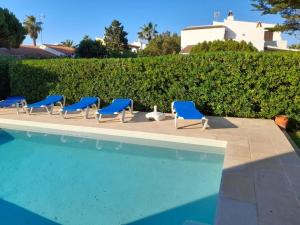 a row of blue chairs next to a swimming pool at Miret in Cala en Bosc