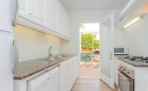 a white kitchen with a sink and a stove at Miret in Cala en Bosc