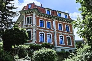 duży, czerwony, ceglany budynek z niebieskimi oknami w obiekcie Ferienwohnung Villa Funcke w mieście Eisenach