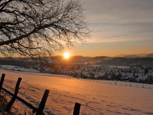 a snowy field with the sun setting in the background at Ferienhaus Pöttgen in Arnsberg +3 photos