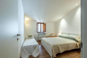 a white bedroom with a bed and a window at Il Teatro in San Gimignano