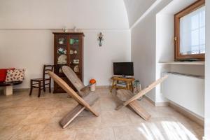 a living room with wooden chairs and a television at Trulli Orma in Martina Franca