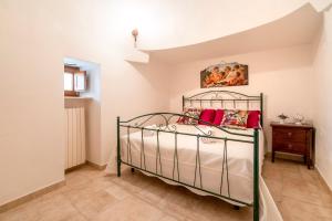 a bedroom with a metal bed with red pillows at Trulli Orma in Martina Franca +28 photos