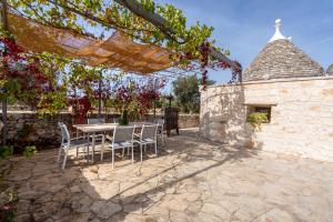 a patio with a table and chairs and a stone wall at Trulli Orma in Martina Franca