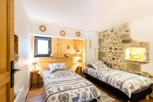 two beds in a room with a stone wall at Gîte L'étable in Sales