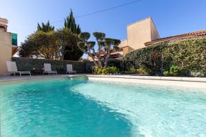 a swimming pool with blue water in front of a building at Villa Salamandre in Port-Saint-Louis-du-Rhône +12 photos