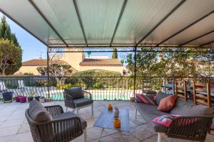 a covered patio with a couch and chairs and a table at Villa Salamandre in Port-Saint-Louis-du-Rhône