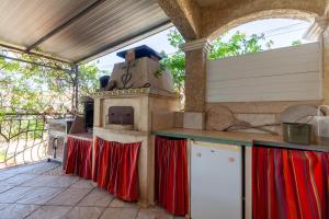 an outdoor kitchen with a stove and red curtains at Villa Salamandre in Port-Saint-Louis-du-Rhône