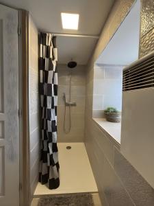 a bathroom with a shower with a black and white shower curtain at Gite de scène in Chamesson
