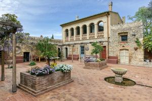 an old stone building with a courtyard with flowers at El Pedró Panoramic in Ventalló
