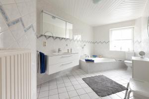 a white bathroom with a tub and a sink at Ferienwohnung Anke Volkmann in Offenbüttel +24 photos