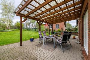 a patio with a table and chairs under a wooden pergola at Ferienwohnung Anke Volkmann in Offenbüttel