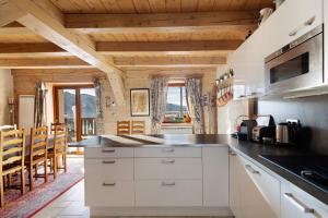 a kitchen with white cabinets and wooden ceilings at Maison de village Puyvalador in Puyvalador +22 photos