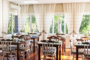 a dining room with tables and chairs and large windows at Tri Pousada Caracol in Canela