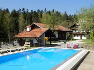 a swimming pool with chairs and a house at Ferienwohnung Geyersberg 704 in Hauzenberg