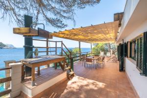 a house with a deck with a table and chairs at Villa Banyalbufar in Banyalbufar