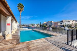 a swimming pool with a deck and a palm tree at Petite maison Aigues Mortes in Aigues-Mortes