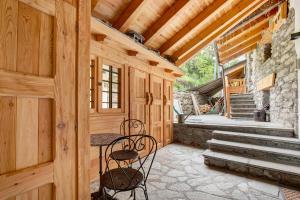 a porch of a cabin with two chairs and a table at Aux Pieds du Malatra' 2 in Saint-Rhémy-en-bosses