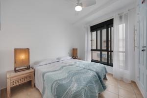 a white bedroom with a bed and a window at Casa Siempreviva in Tarifa
