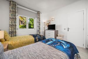 a bedroom with two beds and a tv and a window at Casa Gudrun in Praia do Carvoeiro