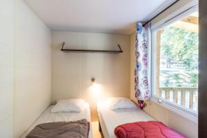 two beds in a room with a window at Mobilhome Le Cocon in Saint-Pompont +15 photos