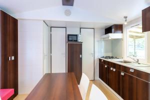 a kitchen with wooden cabinets and a wooden table at Mobilhome Le Cocon in Saint-Pompont