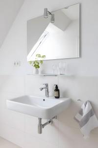 a white bathroom with a sink and a mirror at Strand in Böhl